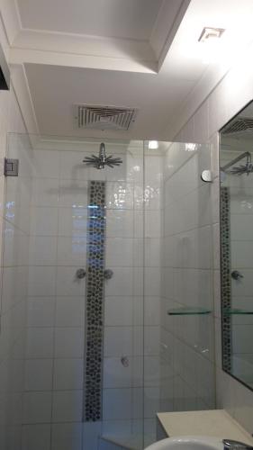 a bathroom with a glass shower with a ceiling fan at Bali Studio in Darwin