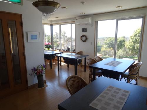 uma sala de jantar com mesas, cadeiras e janelas em Hillside Inn Sirocco em Tateyama