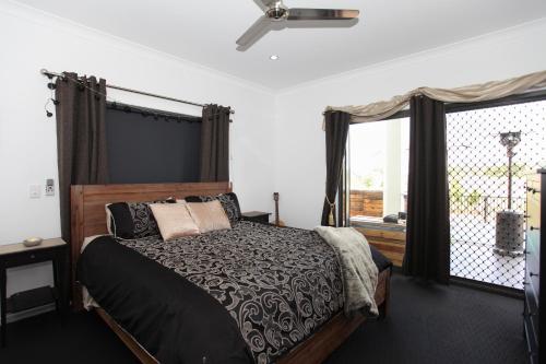 a bedroom with a bed and a large window at Lakeside Deck House in Mackay