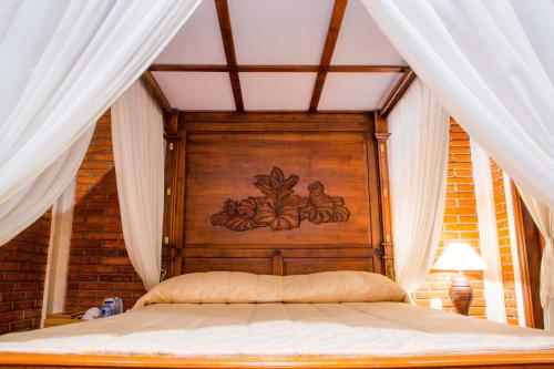 a bed with a wooden headboard in a room with curtains at Ari La Homestay in Ubud