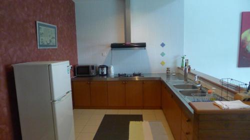 a kitchen with a white refrigerator and a sink at Wesberly Apartments in Kuching