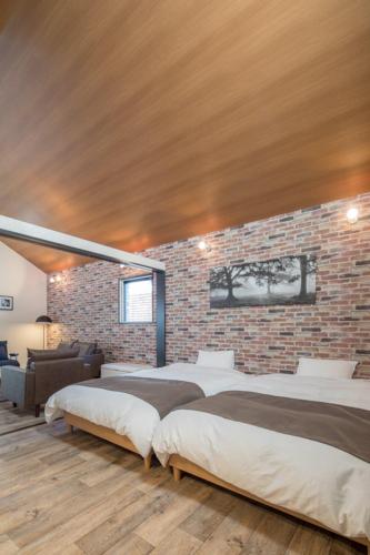 a bedroom with three beds and a brick wall at Sundance Resort Yamanakako in Yamanakako