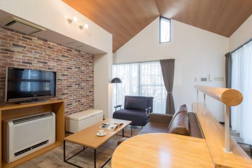 a living room with a couch and a tv at Sundance Resort Yamanakako in Yamanakako