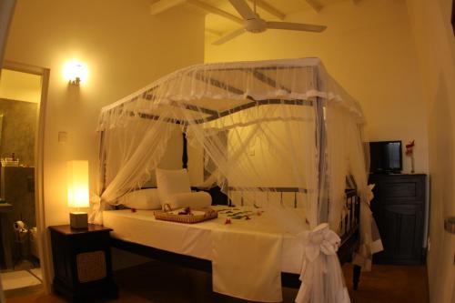 ein Schlafzimmer mit einem weißen Himmelbett und einer Decke in der Unterkunft Oasis Ayurveda Beach Hotel in Ambalangoda