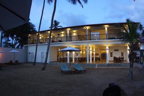 a building with chairs and umbrellas in front of it at Oasis Ayurveda Beach Hotel in Ambalangoda
