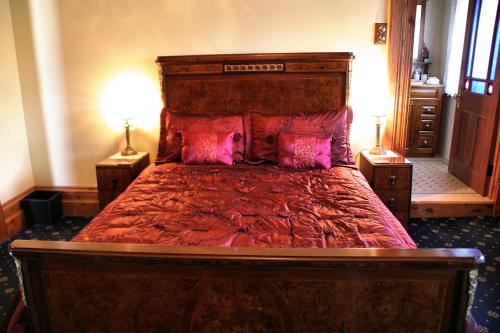 a bedroom with a large bed with red sheets and pillows at Freeman On Ford in Beechworth