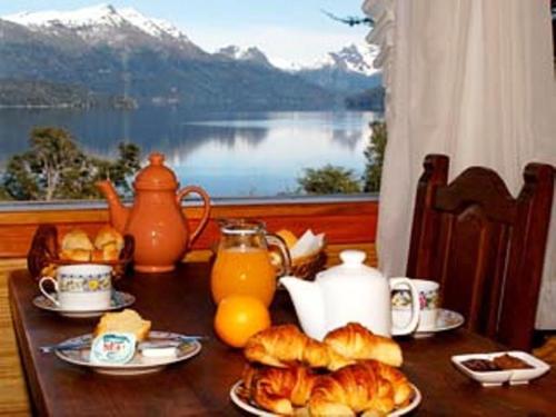 a table with a breakfast of croissants and orange juice at Cabañas Akermann in Villa La Angostura