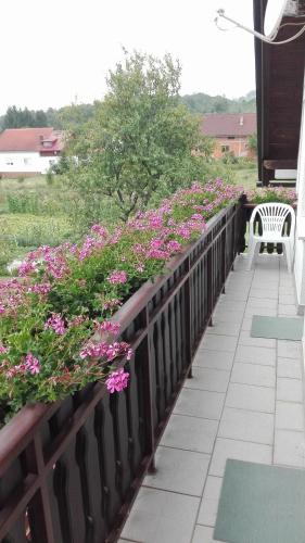 a balcony with pink flowers and a bench at Guest House Adrijana in Seliste Dreznicko