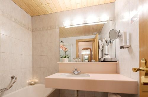 a bathroom with a sink and a tub and a mirror at Hotel Bergkristall in Silbertal