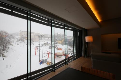 a room with a large window looking out at a snow covered yard at Aya Niseko in Kutchan