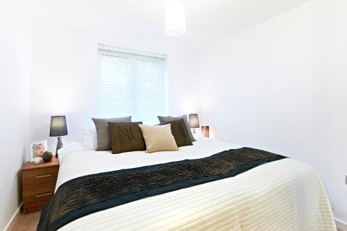 a bedroom with a large bed with white sheets and pillows at Borehamwood - Luxury 2 bed 2 bath apartment in Borehamwood