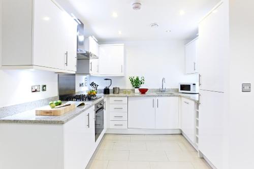 een witte keuken met witte kasten en apparaten bij Borehamwood - Luxury 2 bed 2 bath apartment in Borehamwood