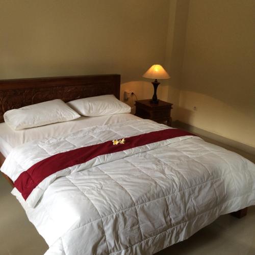 a bedroom with a bed with a red and white blanket at Bagus Homestay in Ubud