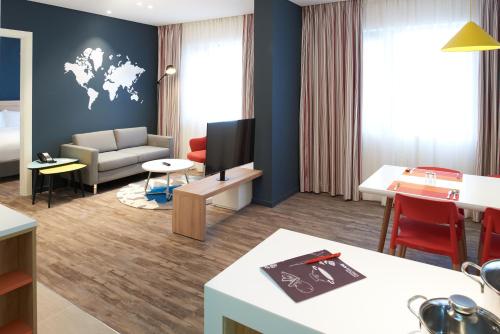 a living room with a couch and a tv on a wall at Ibis Saigon Airport in Ho Chi Minh City