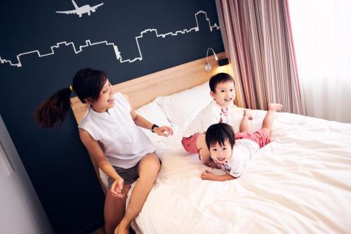 a woman and three children sitting on a bed at Ibis Saigon Airport in Ho Chi Minh City