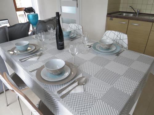 a table with a white table cloth with plates and glasses at Sea Life Apartment in Rewal