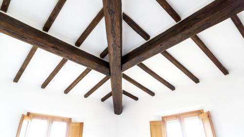 a ceiling with wooden beams in a room with two windows at Casa Ollie in Castel San Gimignano
