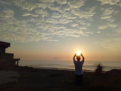 a man standing on the beach looking at the sunset at Time Travelodge Homestay in Zhuangwei