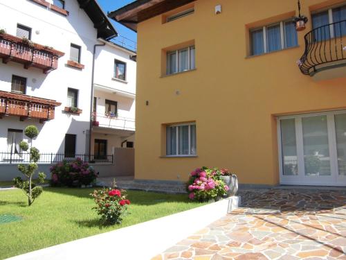 a yellow building with flowers in a yard at Albergo Diffuso Zoncolan in Ovaro