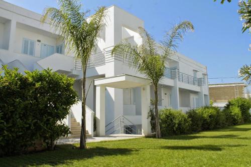 a white building with palm trees in front of it at Blumarine Residence Club in Ostuni