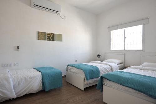 two beds in a room with white walls and a window at Eliyahu Salman Apartment in Jerusalem