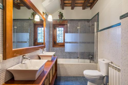 uma casa de banho com 2 lavatórios, um WC e uma banheira em El Aserradero em La Alberca
