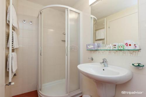 a white bathroom with a shower and a sink at Hotel Belvedere in Verbania