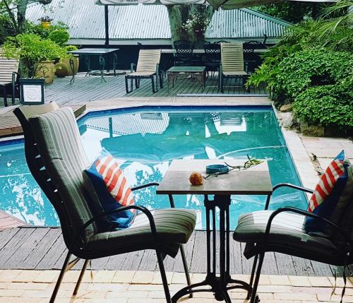 una piscina con 2 sillas y una mesa frente a ella en Elizabeth Manor Guest House, en Johannesburgo