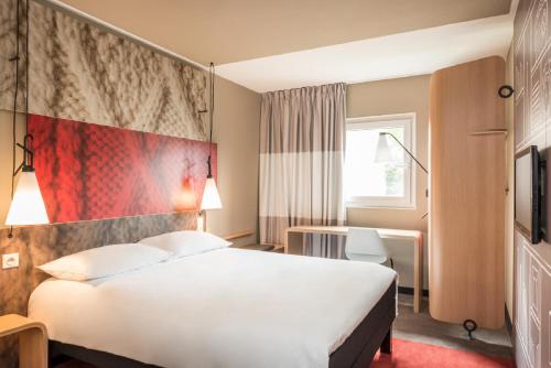 Cette chambre comprend un lit blanc et un mur rouge. dans l'établissement ibis Besançon Centre Ville, à Besançon