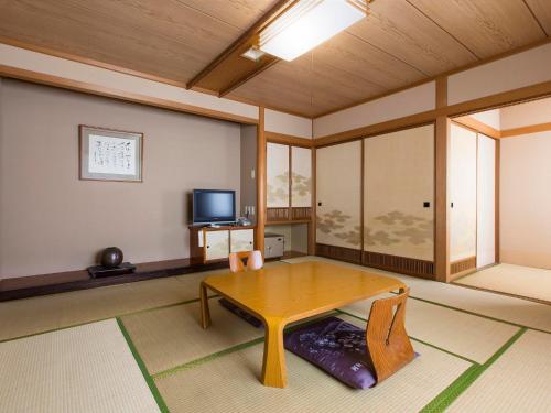 a living room with a wooden table and a tv at Toya Gokirakutei in Lake Toya