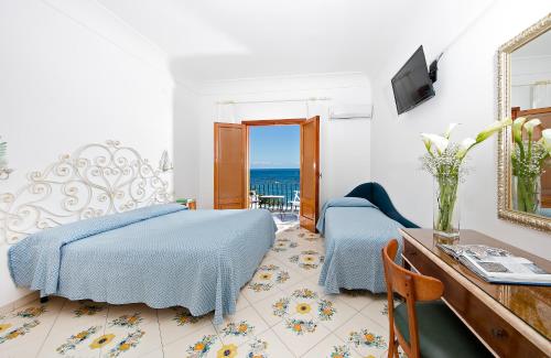 a hotel room with a bed and a desk and a view of the ocean at Hotel Pupetto in Positano