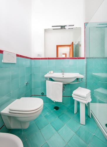 a blue bathroom with a toilet and a sink at Hotel Pupetto in Positano
