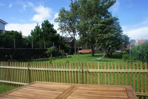 a wooden table in front of a fence with a yard at StoneWood Lodge AL in São Vicente Ferreira