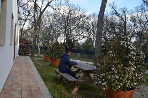 a man sitting on a picnic table in a park at Villaggio Camping Bosco Selva in Alberobello