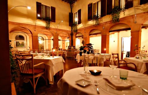 Hotel Locanda Di Bagnara في Bagnara di Romagna: مطعم بطاولات وكراسي مع طاولة قماش بيضاء
