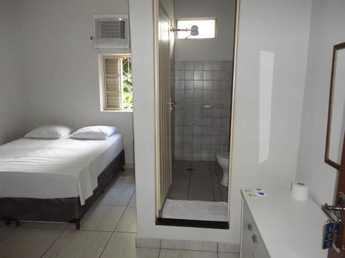 a bedroom with a bed and a bathroom with a shower at Grande Hotel Araçatuba in Araçatuba