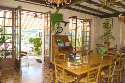 a dining room with a table and some plants at Auberge des Ruines de Merle in Saint-Cirgues-la-Loutre