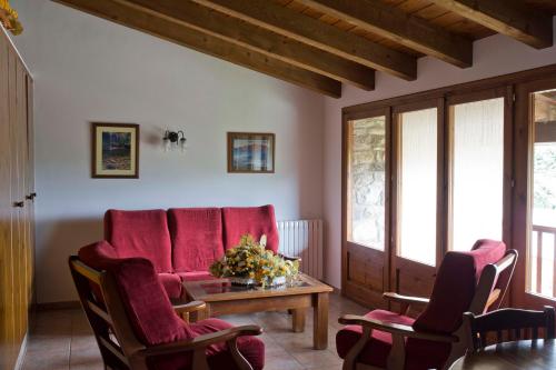 a living room with red chairs and a table at Mas El Ferrés in Joanetes
