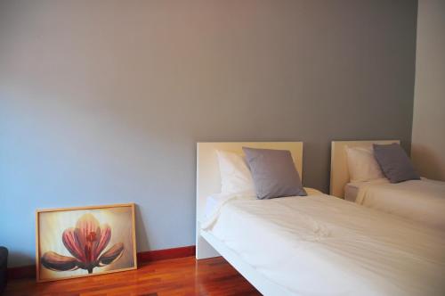 a room with two beds and a painting of a flower at GRAYHAUS Guest House in Petaling Jaya