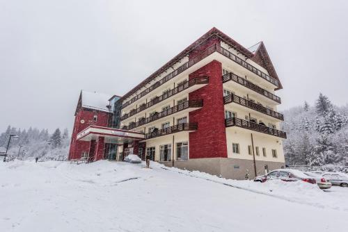 a large building in the snow in a parking lot at Hotel TTS**** Spa&Wellness Covasna in Covasna