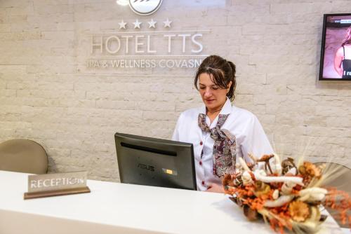 a woman sitting at a table with a computer at Hotel TTS**** Spa&Wellness Covasna in Covasna