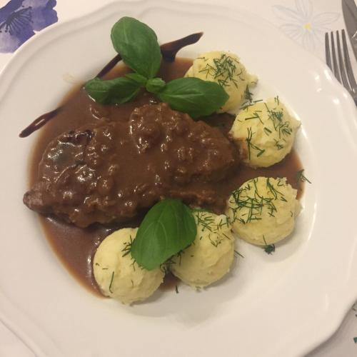 a plate of food with meat and potatoes and gravy at Dom św. Józefa in Szczecin