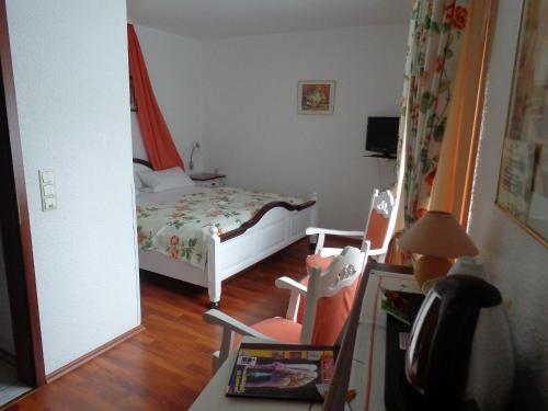 ein kleines Schlafzimmer mit einem Bett und zwei Stühlen in der Unterkunft Hotel Zur Lohe in Merzenich