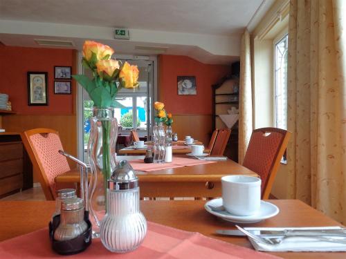 a dining room table with a vase of flowers on it at Hotel Zur Lohe in Merzenich