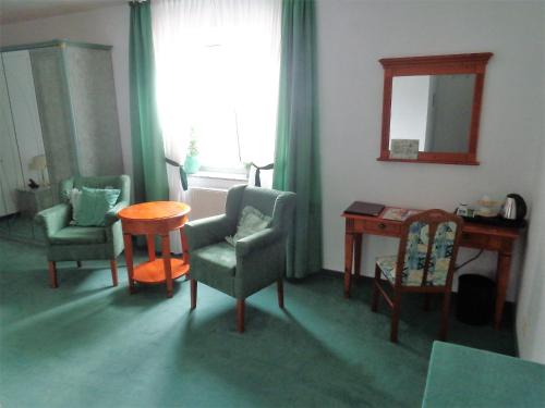 a living room with chairs and a table and a mirror at Hotel Zur Lohe in Merzenich