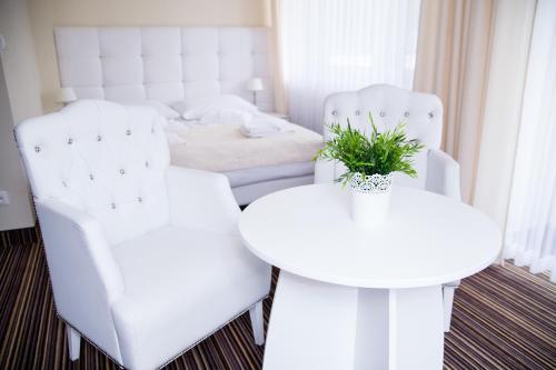 a room with two white chairs and a table and a bed at Hotel Morskie Oko in Jurata