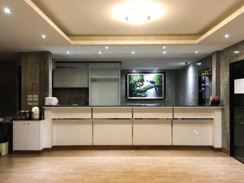 Il comprend une cuisine avec des placards blancs et une télévision à écran plat. dans l'établissement Nai Suan Inn, à Ban Doem Bang