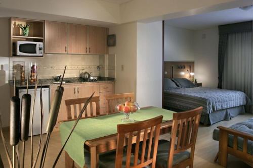 cocina y comedor con mesa y cama en Cóndor Suites Apart Hotel en Mendoza