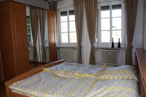 a bed in a bedroom with two windows at Weingut Koch in Neumagen-Dhron