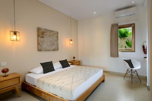 a bedroom with a bed and a chair and a window at Canggu Beach Apartments in Canggu